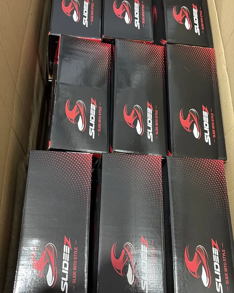 A carton filled with printed black and red Slideez boxes, one pair per box